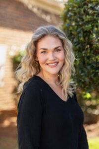 Smiling blonde woman named Alexa Little wearing a black shirt.